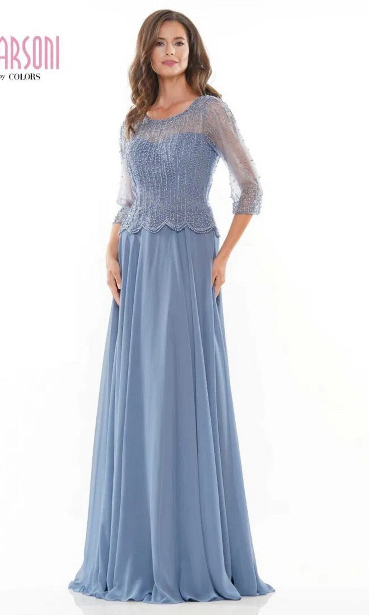 A woman models the Marsoni M312 long formal dress in slate blue, featuring an A-line skirt and beaded sheer sleeves, standing against a plain white background.